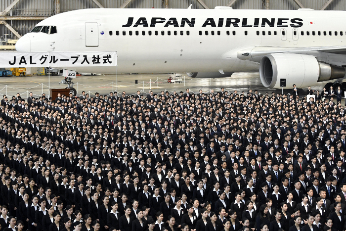 Los nuevos empleados de la aerolínea Japan Airlines asisten a una ceremonia de bienvenida en el hangar de mantenimiento del aeropuerto de Haneda en To