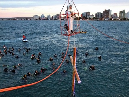 El sacerdote con escafandra y la cruz son transportados al mar