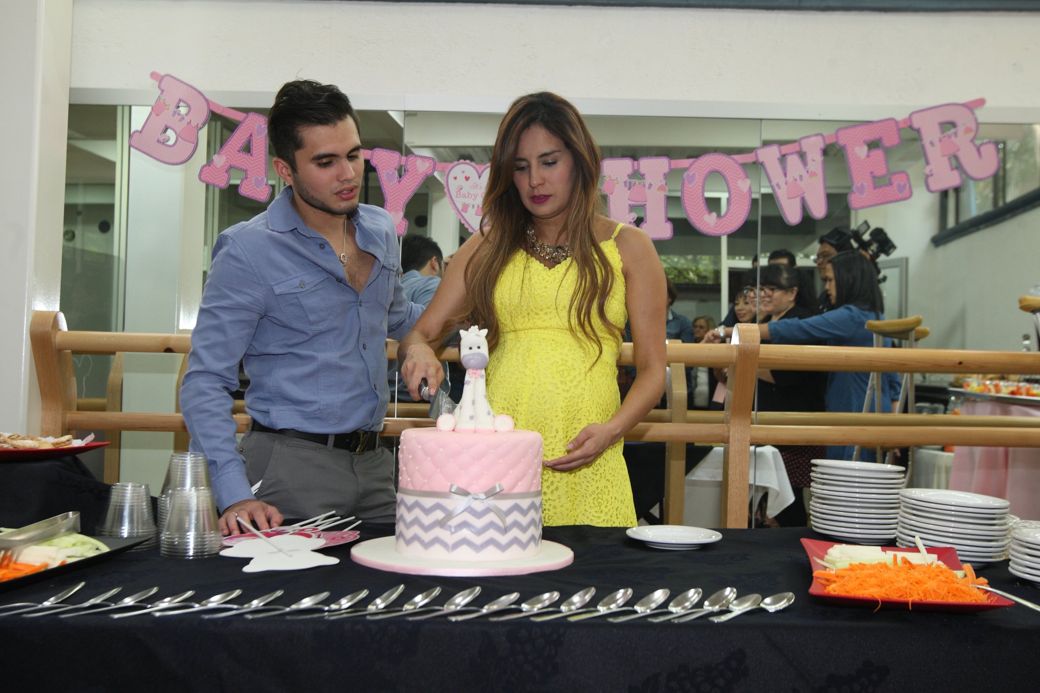 Paola e Iván parten el pastel al final del baby shower.