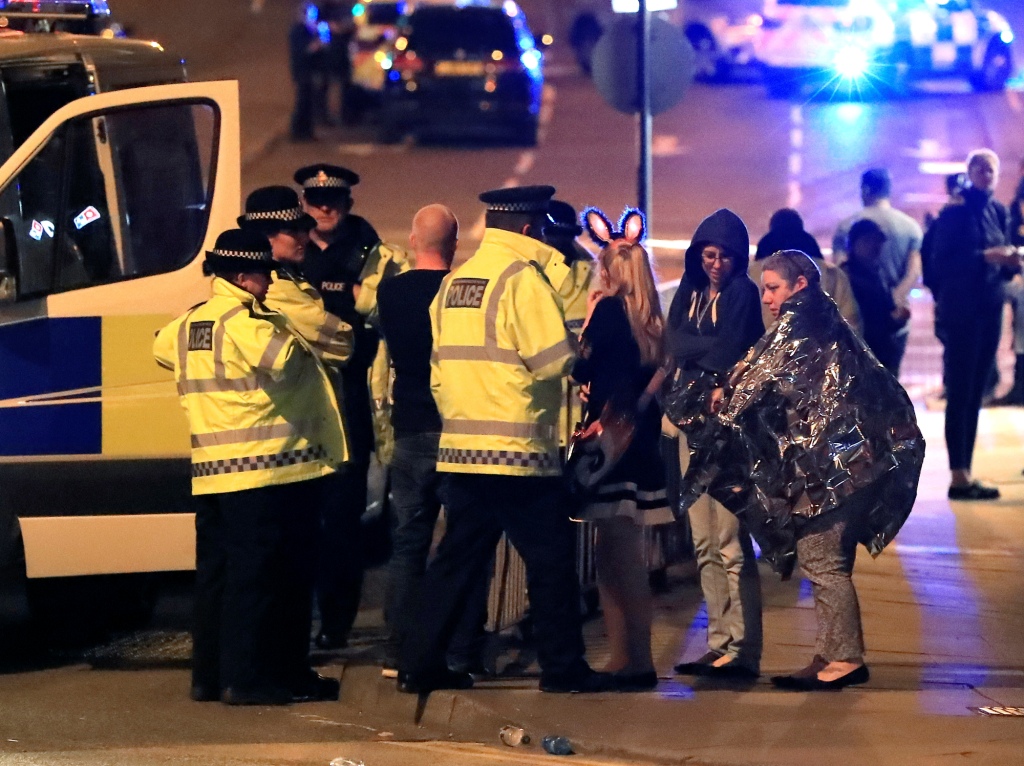 Policías hablan con algunos asistentes del concierto de Ariana Grande tras haber sido evacuados de la Manchester Arena.