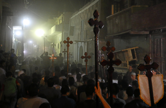 Los dolientes llevan cruces y marchan después del funeral de los cristianos coptos que murieron en Minya, Egipto.