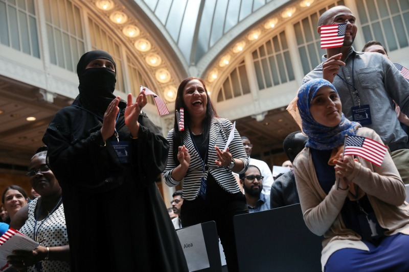 Migrantes sonríen durante una ceremonia de Naturalización de Servicios de Ciudadanía e Inmigración en la Biblioteca Pública de Nueva York.