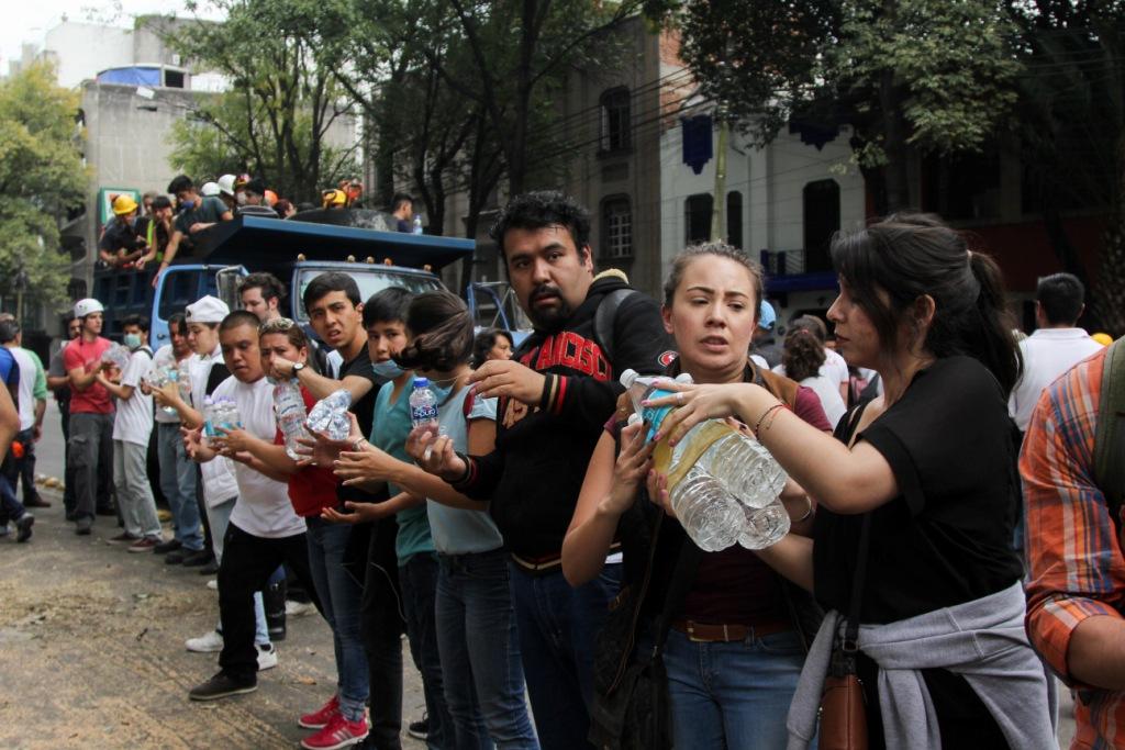 Los voluntarios hacen cadenas humanas y se pasan los productos de mano en mano hasta el camión que los transportará.