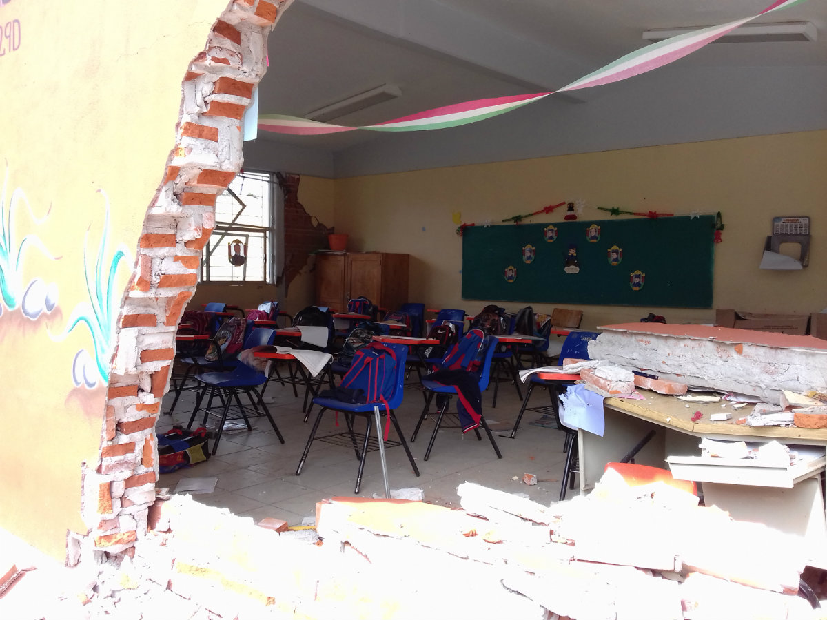 La escuela primaria quedó inservible y en uno de sus salones hay un boquete que deja ver el escritorio, dañado por una enorme piedra, así como las but