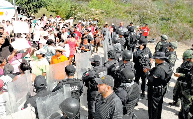 Pobladores de la comunidad de Mezcala son contenidos por una valla de policías estatales. 