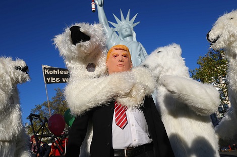 Un manifestante caracterizado del presidente de Estados Unidos, Donald Trump, es abrazado por botargas de osos polares.