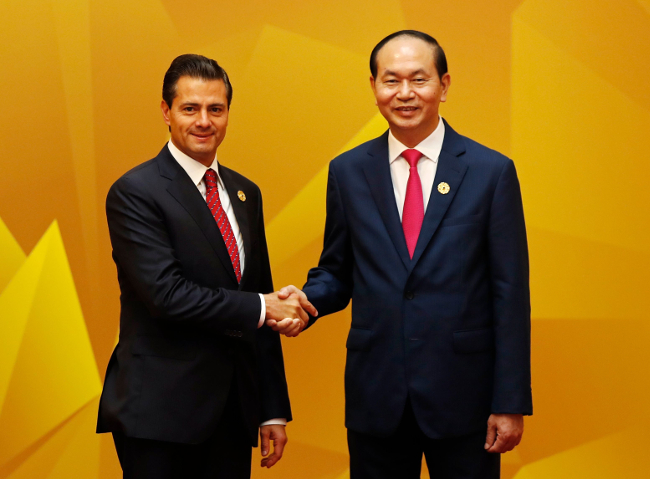 El presidente Enrique Peña Nieto saluda al presidente vietnamita, Tran Dai Quang, al arribar a la reunión de líderes económicos de APEC.