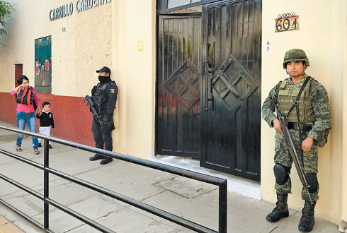 Un policía federal y un militar vigilan la entrada de los alumnos a un centro educativo de Chilapa. 