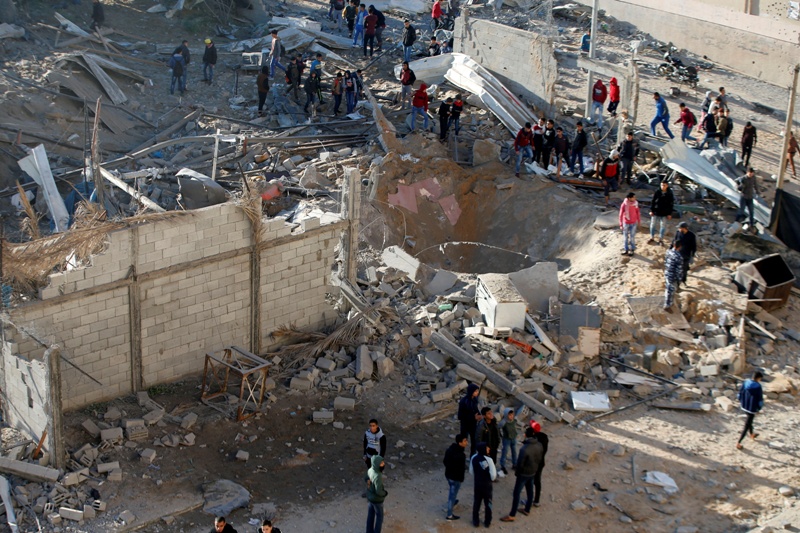 Varios palestinos se reúnen alrededor de los destrozos que dejó el ataque aéreo israelí en el norte de Gaza 