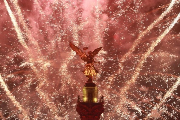 Los fuegos artificiales iluminan el Ángel de la Independencia, durante el concierto por la llegada del año nuevo.