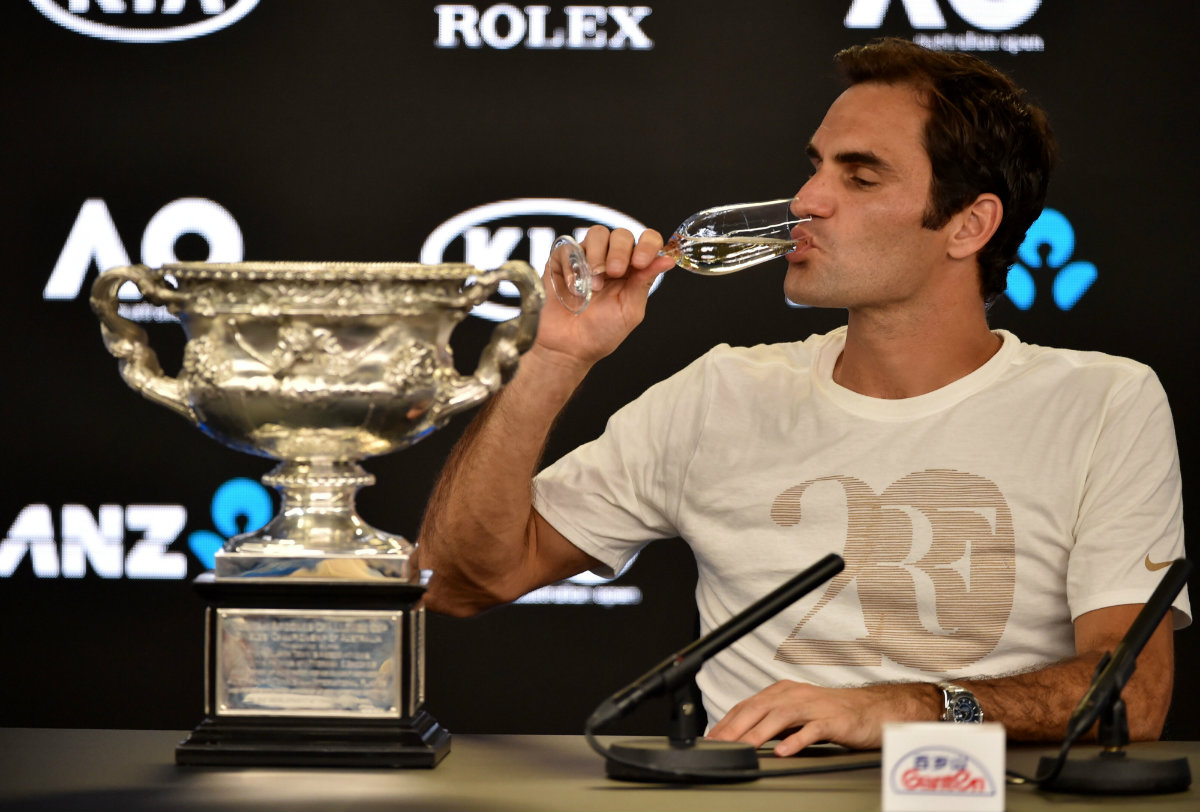 Roger Federer toma champán junto a su trofeo del Abierto de Australia