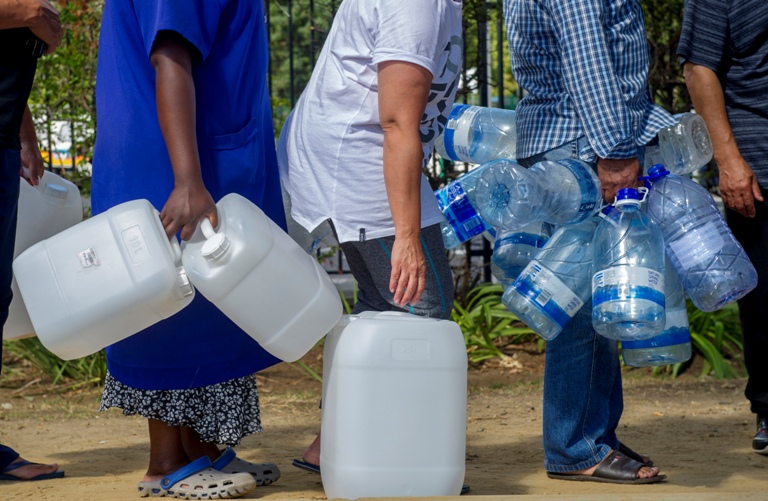 La gente hace cola para abastecerse de agua de un manantial natural en Ciudad del Cabo.