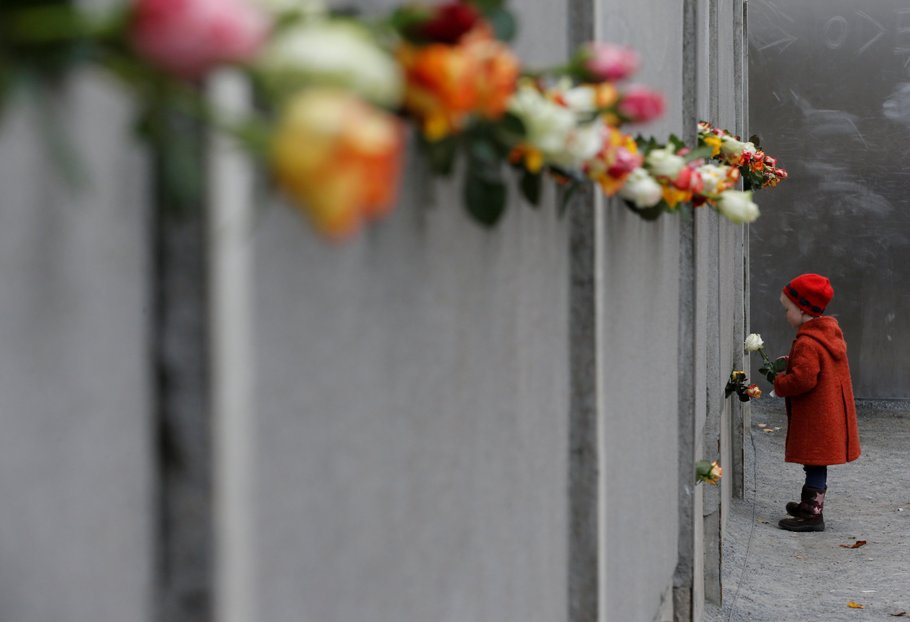 Una niña coloca una rosa en el memorial del Muro de Berlín en Bernauer Strasse, durante la ceremonia conmemorativa del 25 aniversario de la caída del 