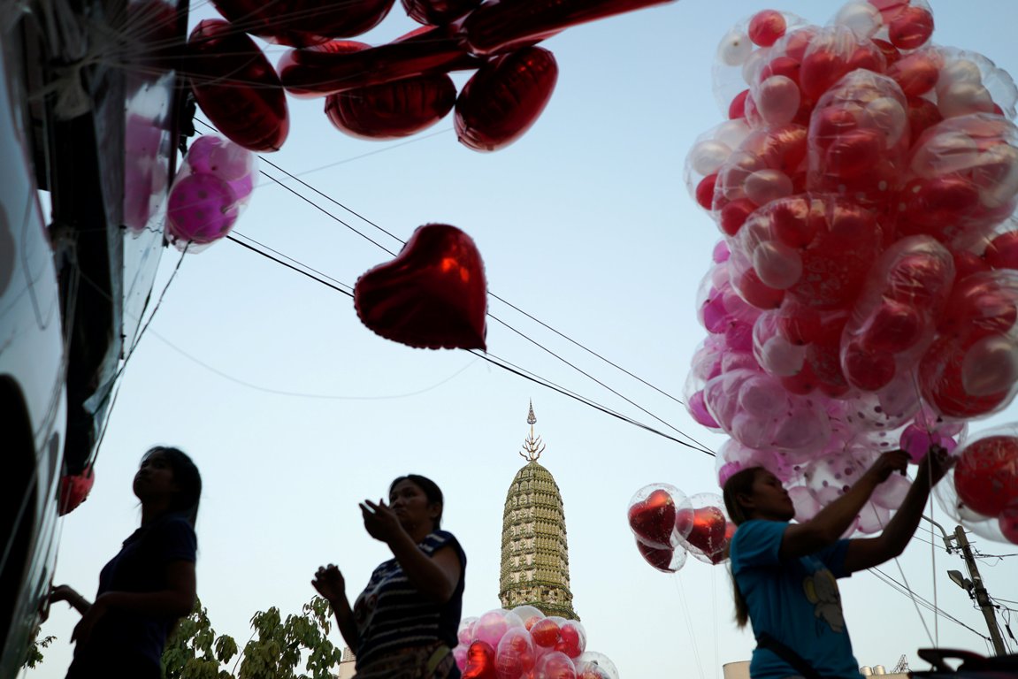 Vendedores ambulantes que ofrecen globos frente a un templo en Bangkok.