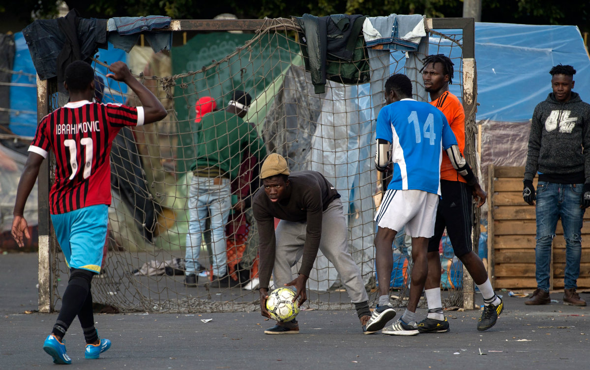 Migrantes subsaharianos jugando futbol en una cancha improvisada