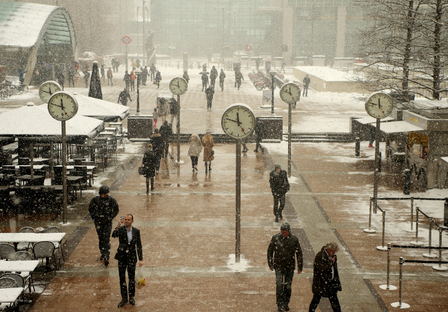 La gente camina a través de Canary Wharf durante una ráfaga de nieve en Londres, Gran Bretaña.