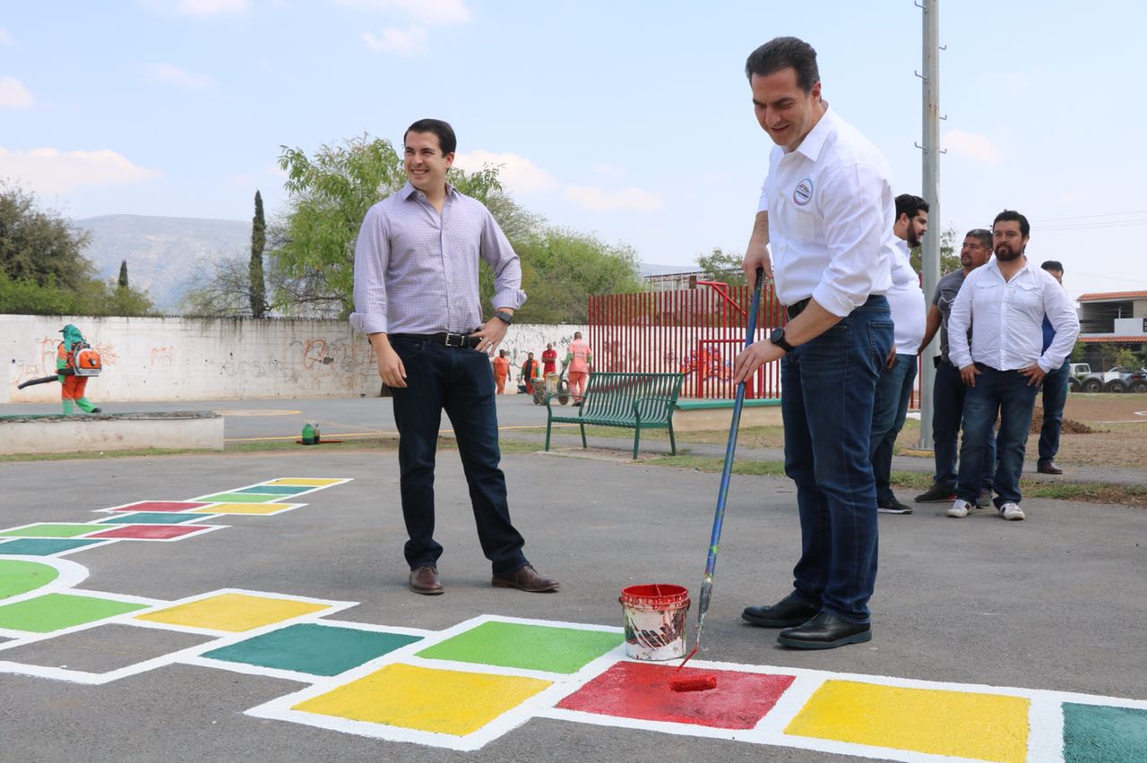 El alcalde Adrián de la Garza pinta una rayuela en el parque de la colonia.