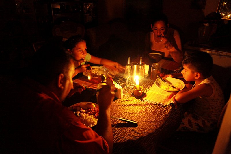 Una familia usa velas para iluminar la mesa mientras durante un apagón en San Cristóbal, Venezuela.