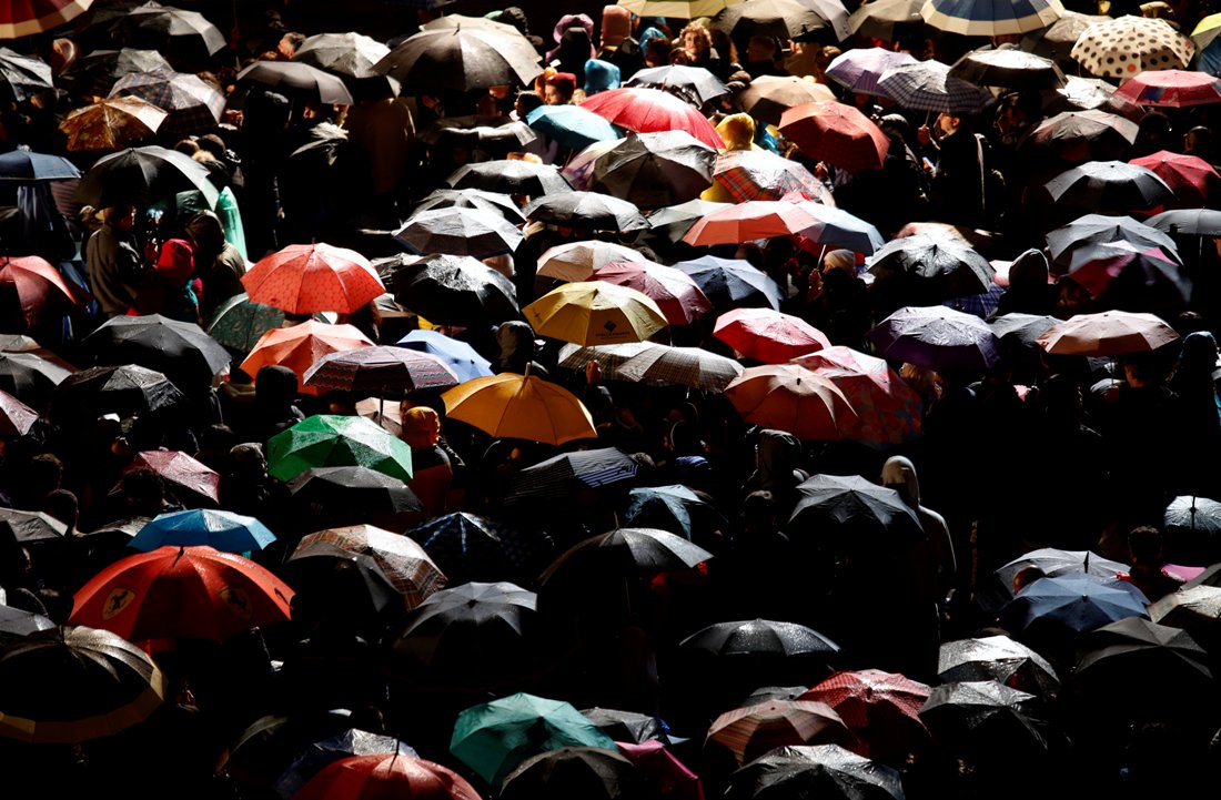 Cientos de personas se cubren de la lluvia al asistir a la representación del Viacrucis en el Coliseo.