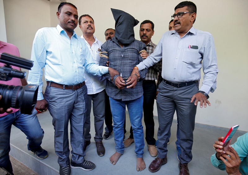 Policías custodian a Harshsai Gurjar, acusado de la agresión sexual y muerte de una niña de 11 años en Ahmedabad.