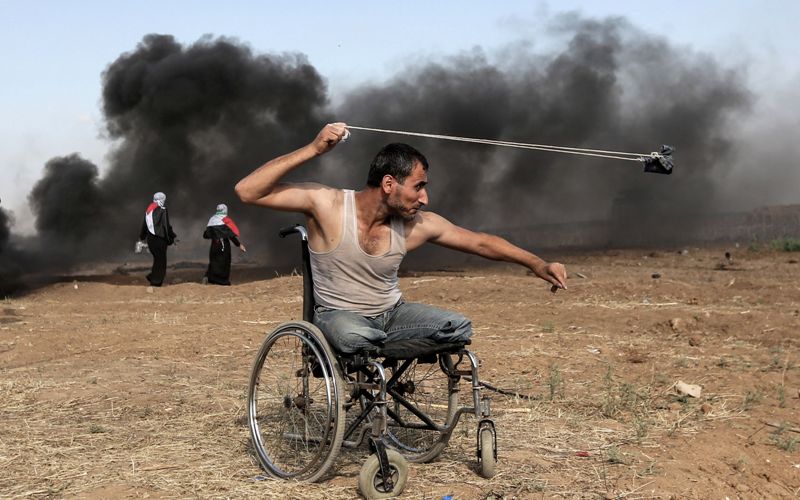 Un palestino arroja piedras durante los enfrentamientos con las fuerzas israelíes a lo largo de la frontera con la Franja de Gaza. (AFP)