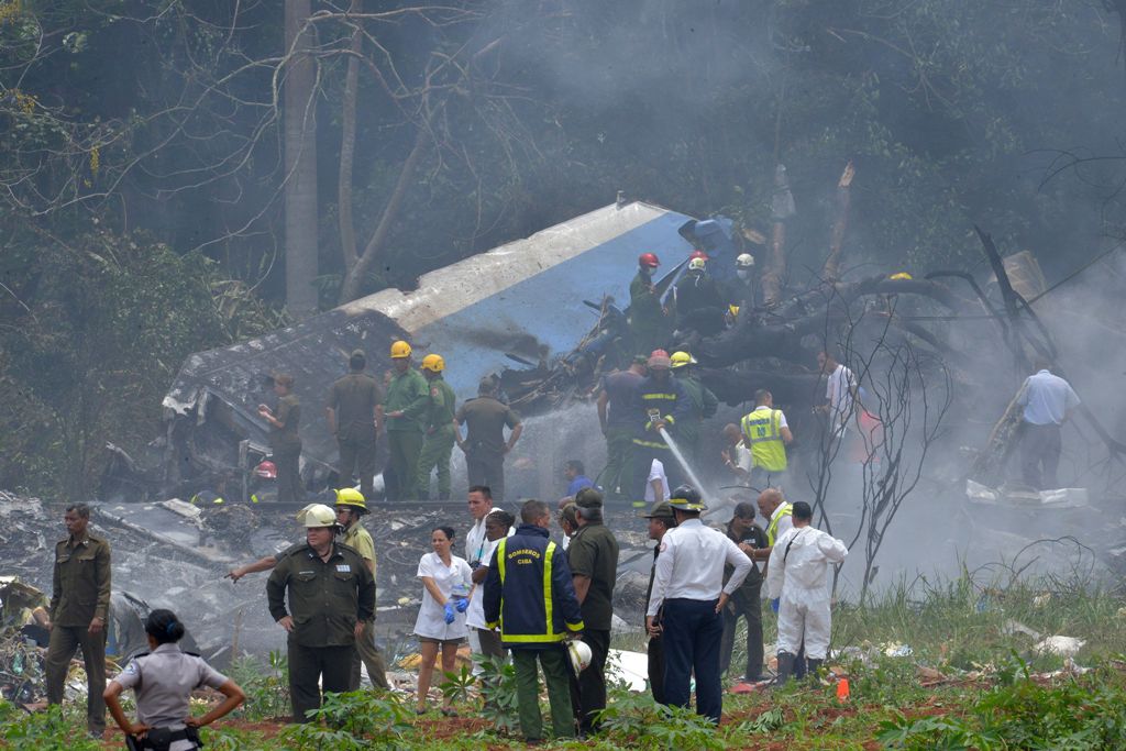 Al fondo se observa a rescatistas y bomberos sobre los restos del avión.