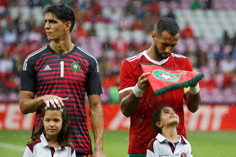 Mehdi Benatia protege a una niña de la lluvia con el banderín (EFE)