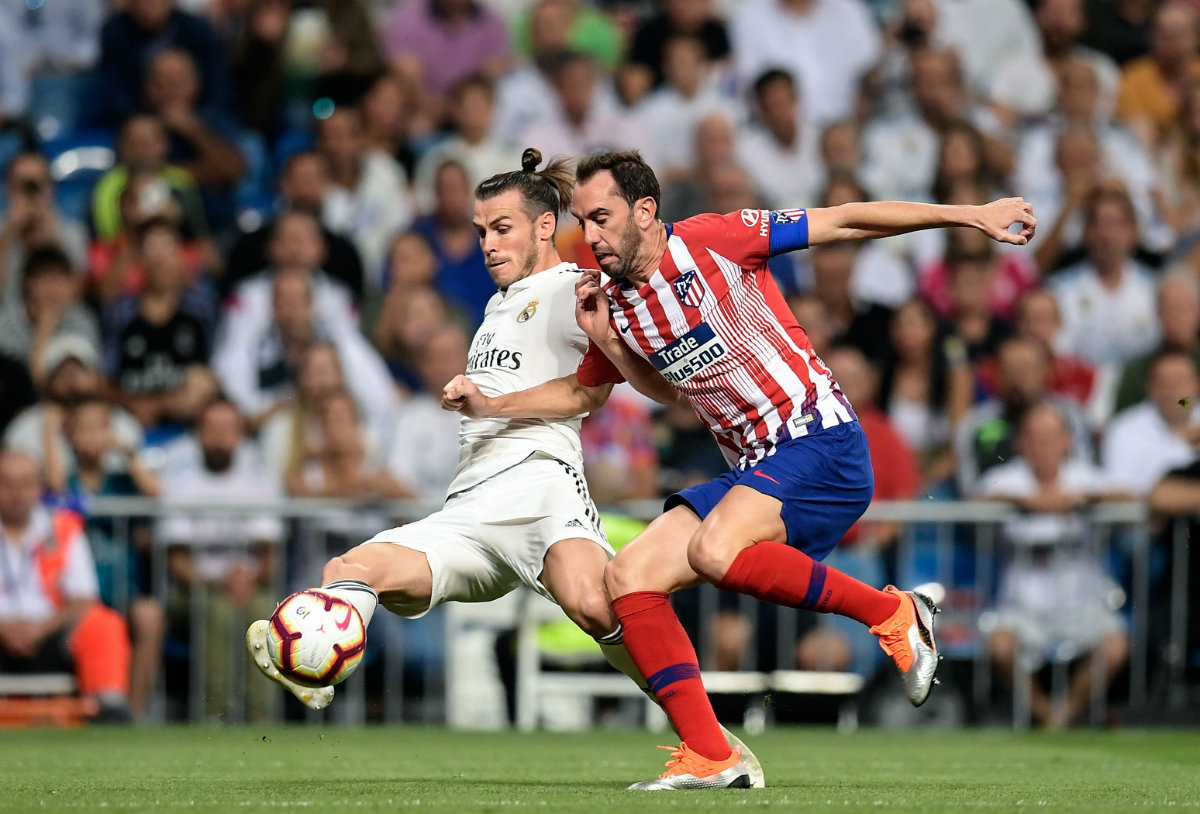Gareth Bale y Diego Godín durante el derbi madrileño (AFP)