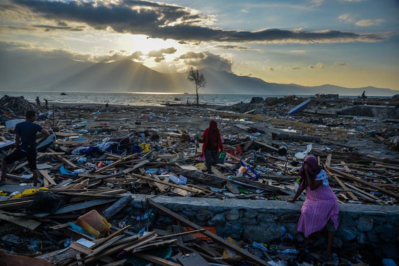 Indonesia- Bajo un atardecer, algunos habitantes buscan artículos entre los escombros en el pueblo Mamboro. (EFE)