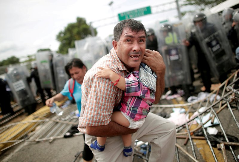 Un hombre que viaja con la Caravana protege a un bebé. (Reuters)