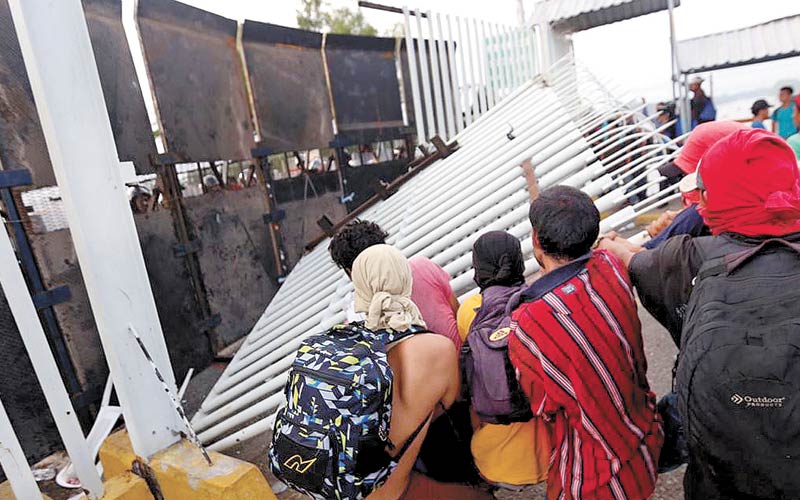 Viajeros atravesaron el puente Suchiate; se toparon con la reja metálica de acceso a México. Ahí estaban desplegados efectivos de la PF. (Nelly Salas)