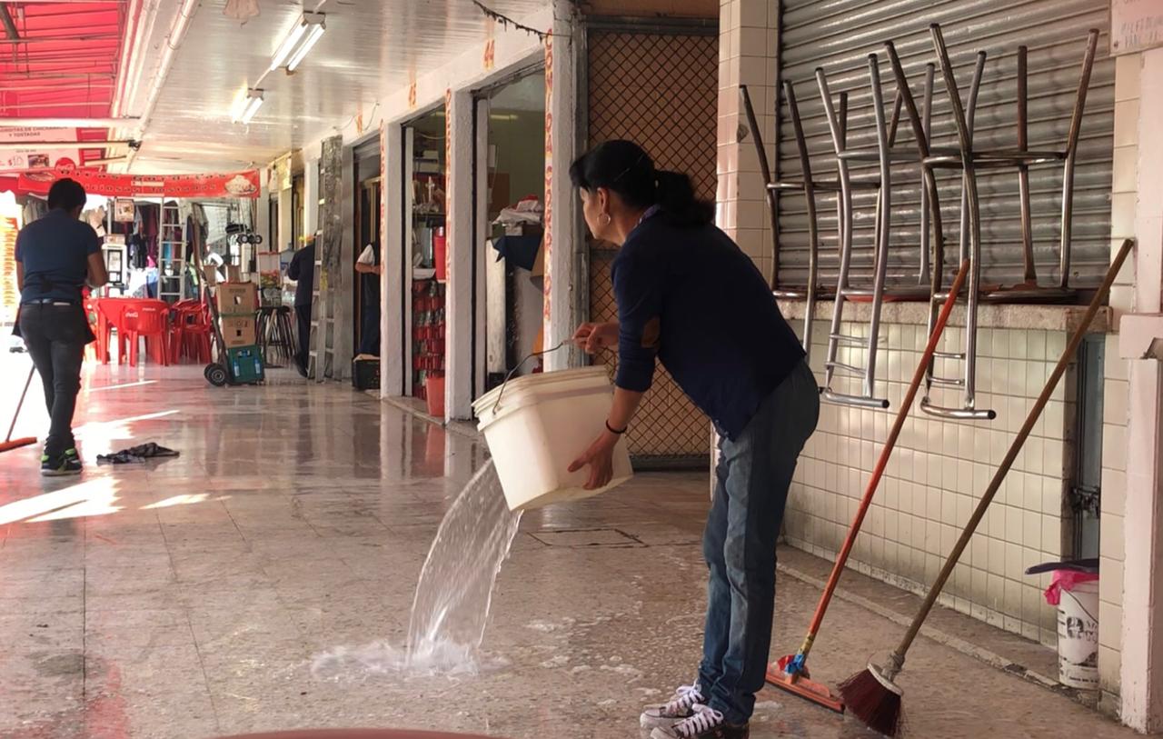 Locatarios en la alcaldía Cuauhtémoc lavan a 'cubetazos' el piso. | Selene Flores