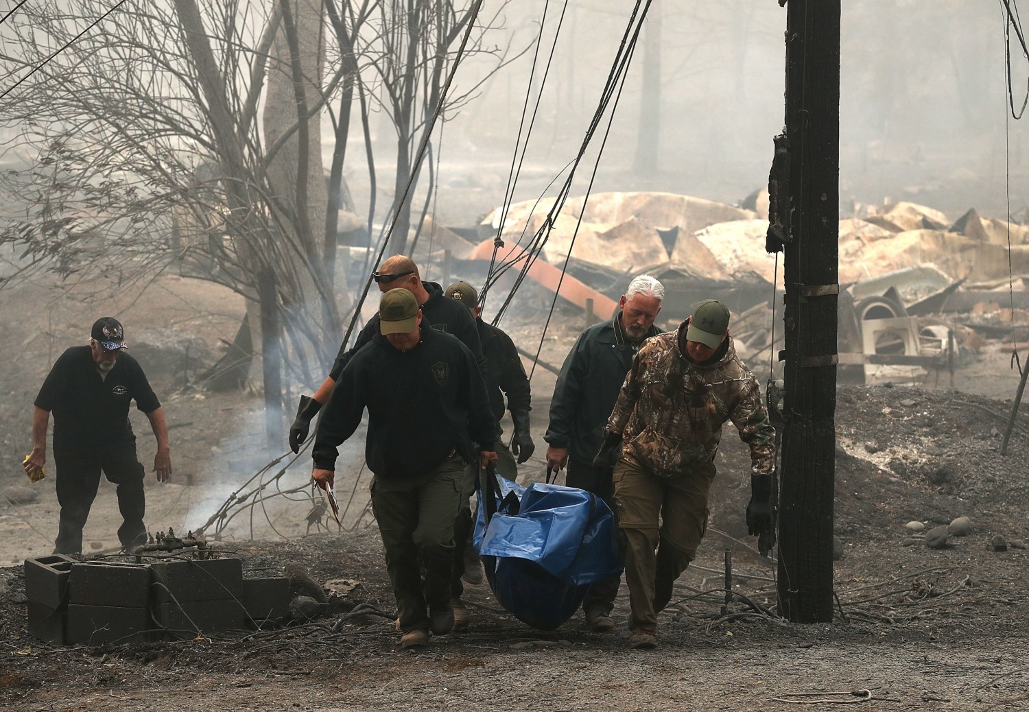 Equipos de rescate trasladan uno de los cuerpos localizado entre los restos de casas calcinadas en Paradise. (AFP)