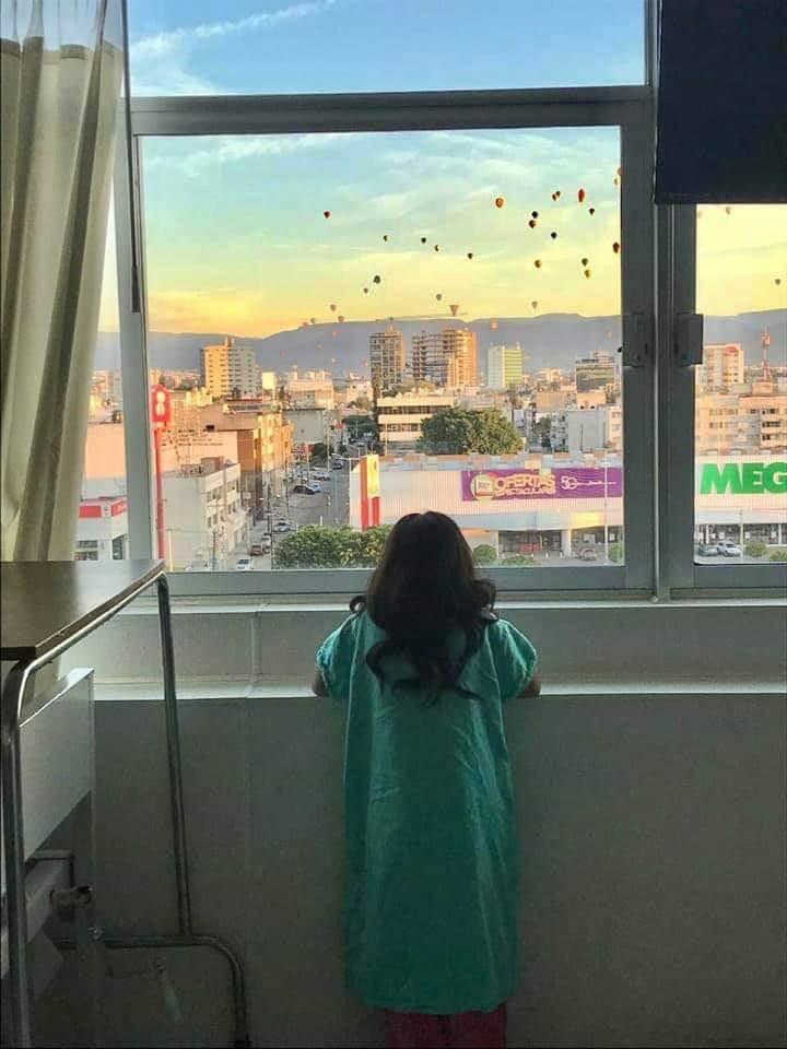 La pequeña admira los globos desde el cuarto del hospital