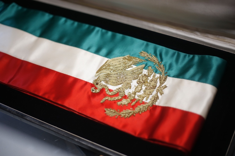 La banda presidencial tiene los colores de la bandera en franjas iguales y lleva encima el escudo nacional bordado en hilo dorado, a la altura del pec