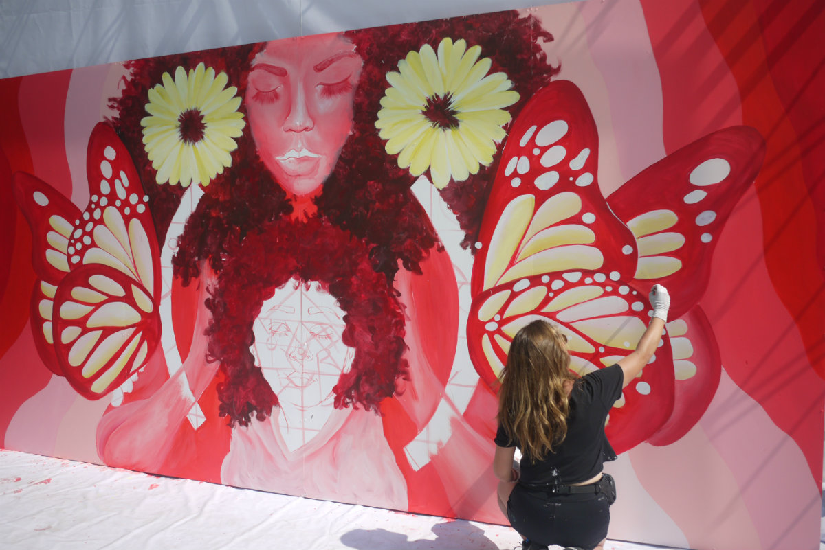 La muralista Sofía Castellanos pintando su obra para contribuir a la Carrera Telcel RED (Cortesía)