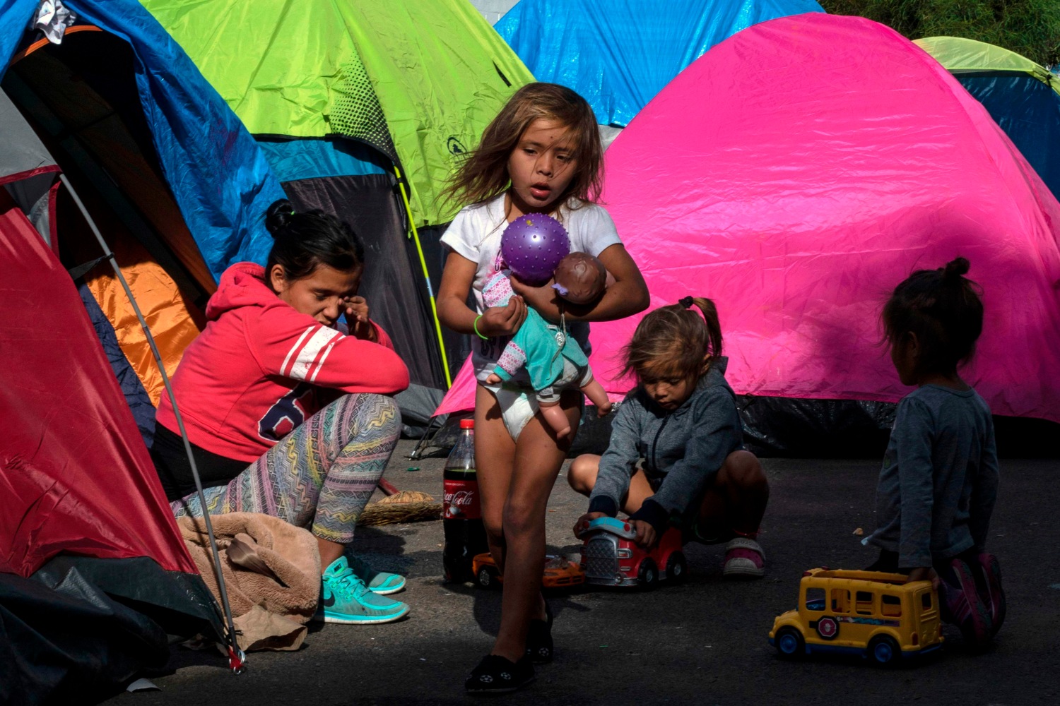 Niños de la caravana migrante juegan en la calle cerca de un refugio temporal cerrado a pocos metros de la frontera con EU. (AFP)