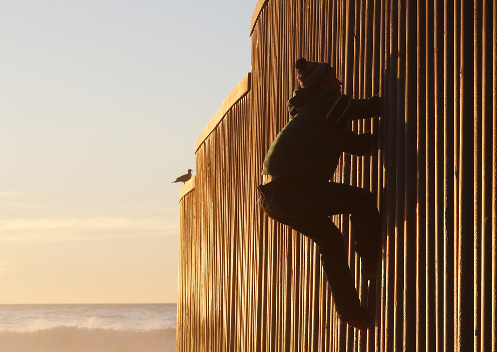 Tijuana- Un migrante hondureño trepa el muro fronterizo en México. AP/ Rebecca Blackwell