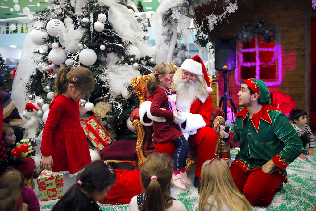 Rumania- Los niños se sientan alrededor de un hombre vestido con un traje de Papá Noel durante un espectáculo navideño. AP