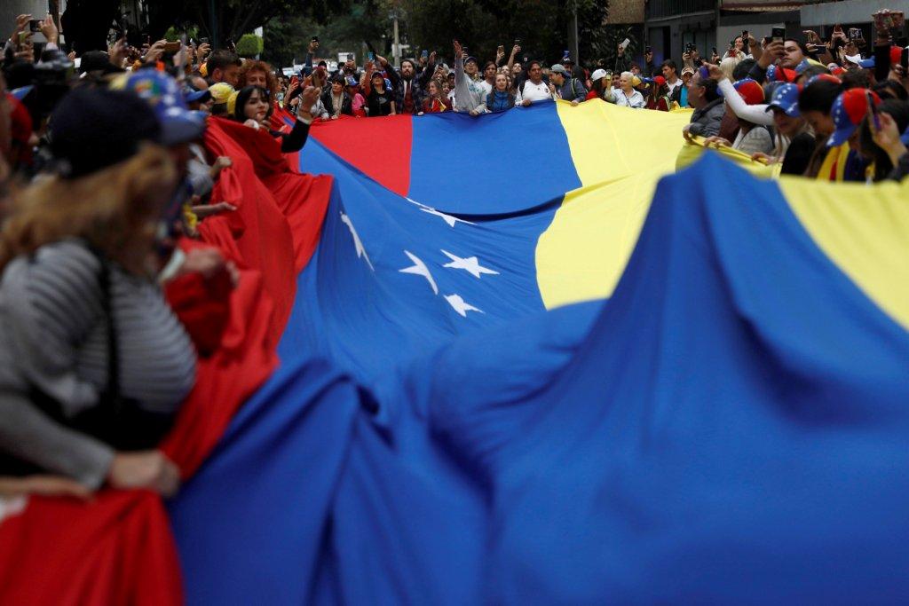 Un grupo de personas sostiene una bandera de Venezuela para apoyar a Juan Guaido, frente a la Embajada de ese país en la Ciudad de México. (Reuters)