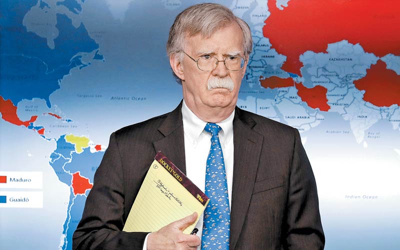 John Bolton con su libreta en mano donde se lee “5,000 tropas a Colombia”. Tras él, un mapa donde México aparece “pro Maduro”. (AP)