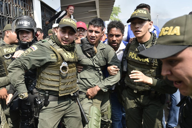 Policías colombianos acompañan a un oficial de policía venezolano que desertó de Venezuela en el puente internacional Simón Bolívar, en Cúcuta, Colomb