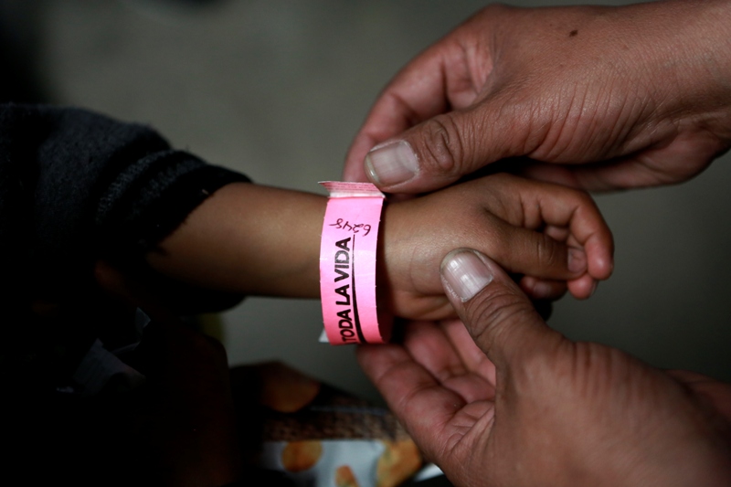 Un niño usa una pulsera con un número que indica su lugar en la fila para presentar su petición de asilo en EU en el interior de un albergue. (AP)