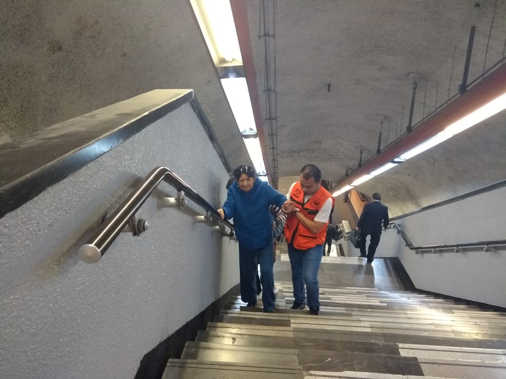 Personal del Metro, identificado con chaleco naranja, ayuda a personas adultas mayores a subir escaleras. (Especial)