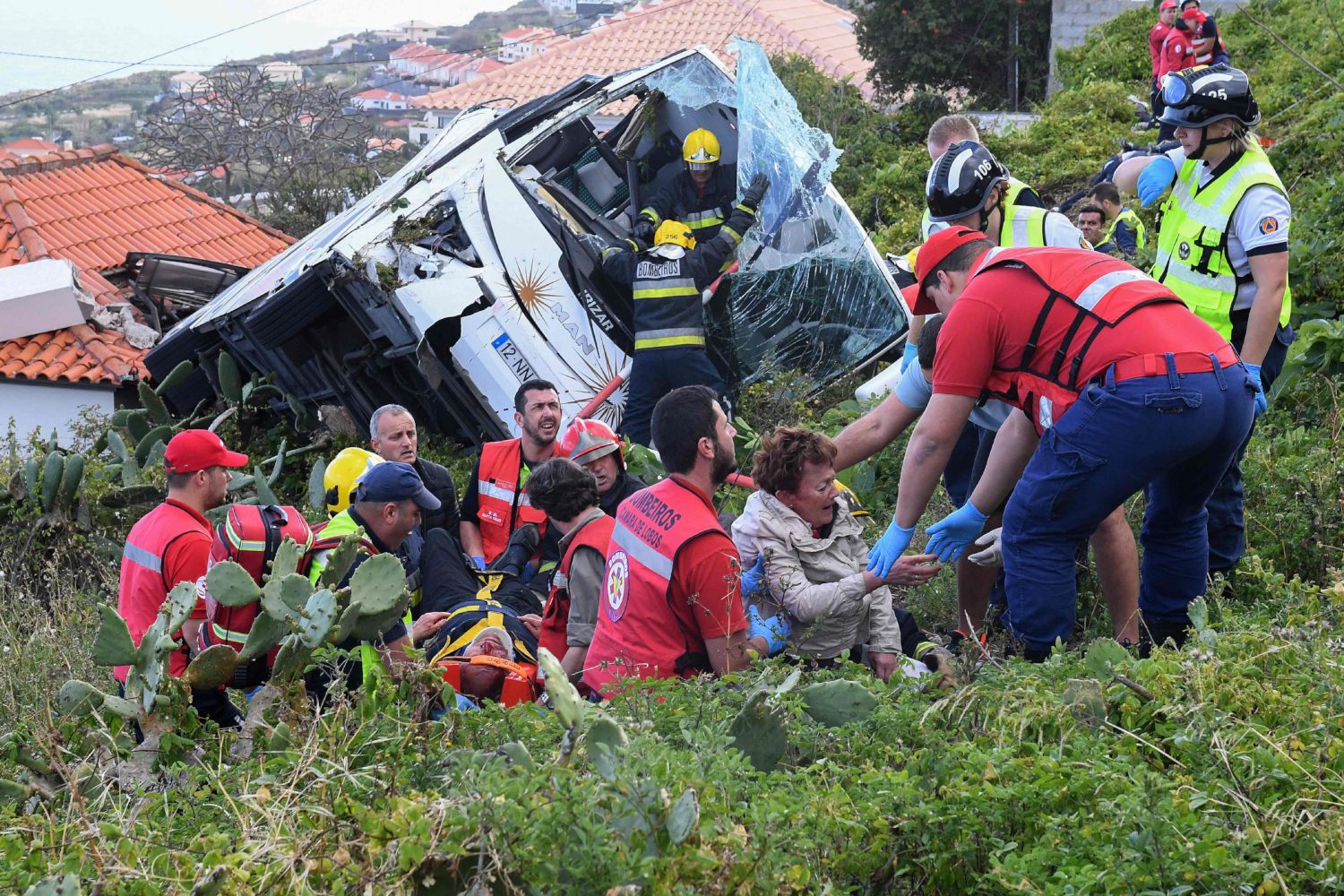 Bomberos auxilian a los turistas tras el accidente del autobús en el que viajaban en Portugal. (AFP)