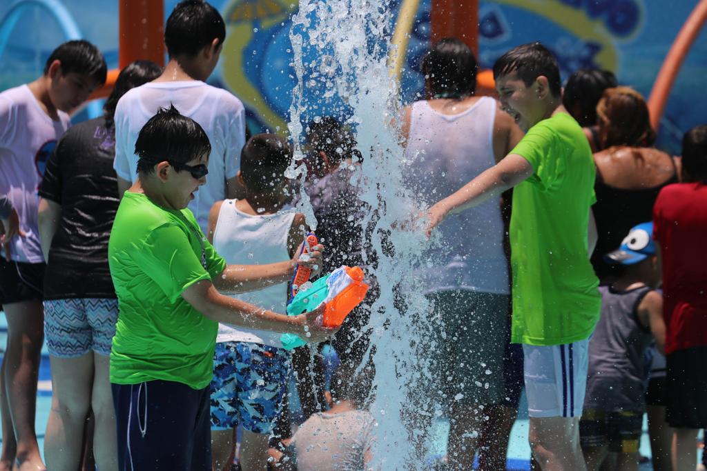 Los niños aprovechan los chorros de agua para cargar sus armas en el Parque Acuático Gotita Sonriente. (Jorge Carballo)