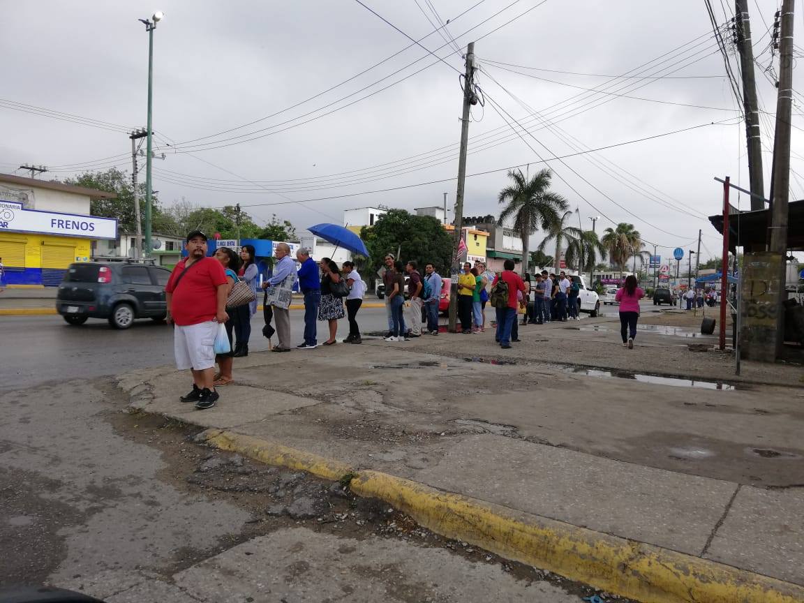 Ciudadanos esperan el escaso transporte público en la lluvia