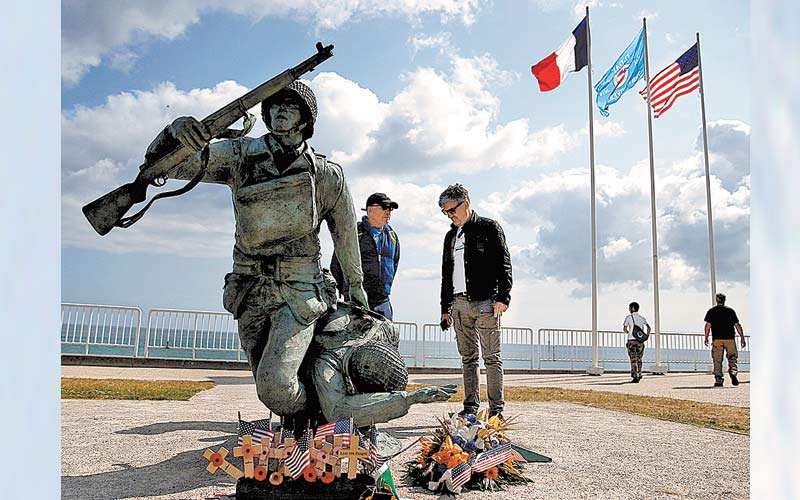 Visitantes observan el monumento a la llegada de soldados de EU a Vierville-sur-Me. (Reuters)