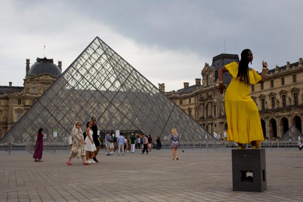 Francia. Una mujer posa frente a la pirámide del Museo de Louvre en París mientras los visitantes caminan por la plaza (AP)