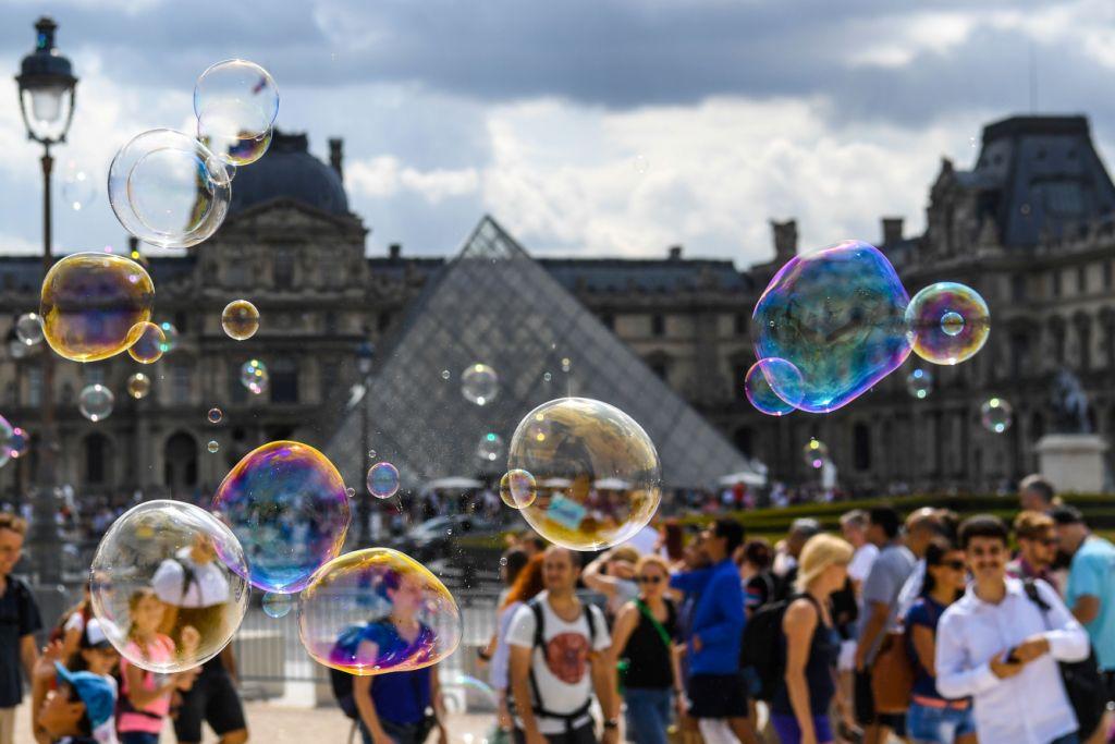 Francia. Turistas lanzan burbujas frente a la pirámide del Museo de Louvre de París. (AFP)